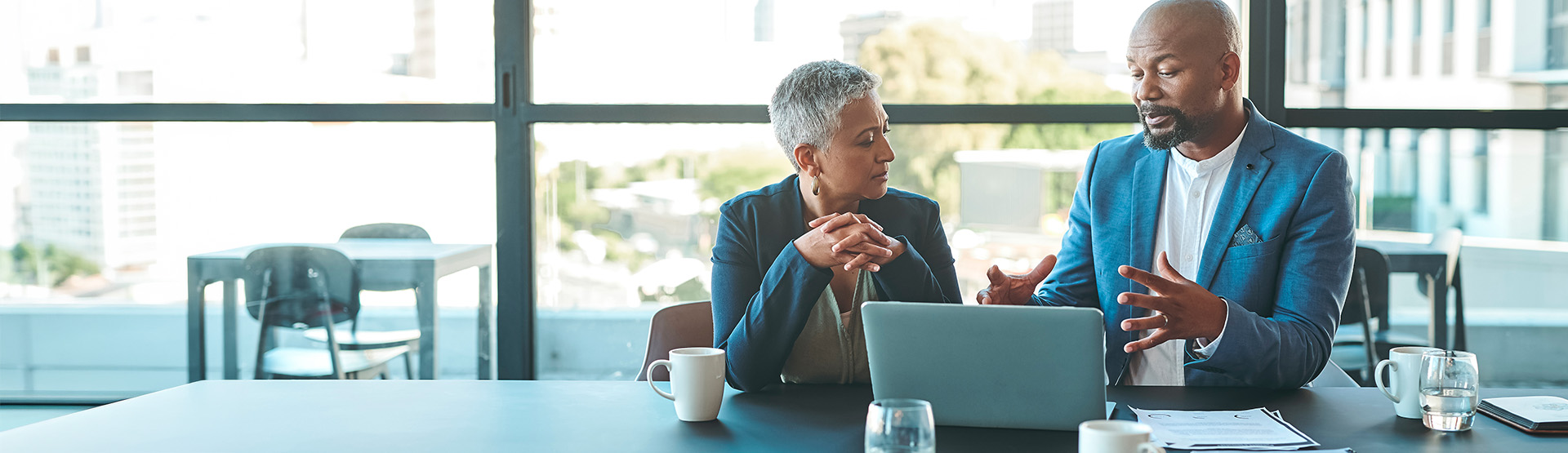Man sitting at desk giving presentation to female colleague