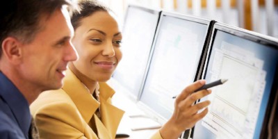 Two office workers looking at a computer screen